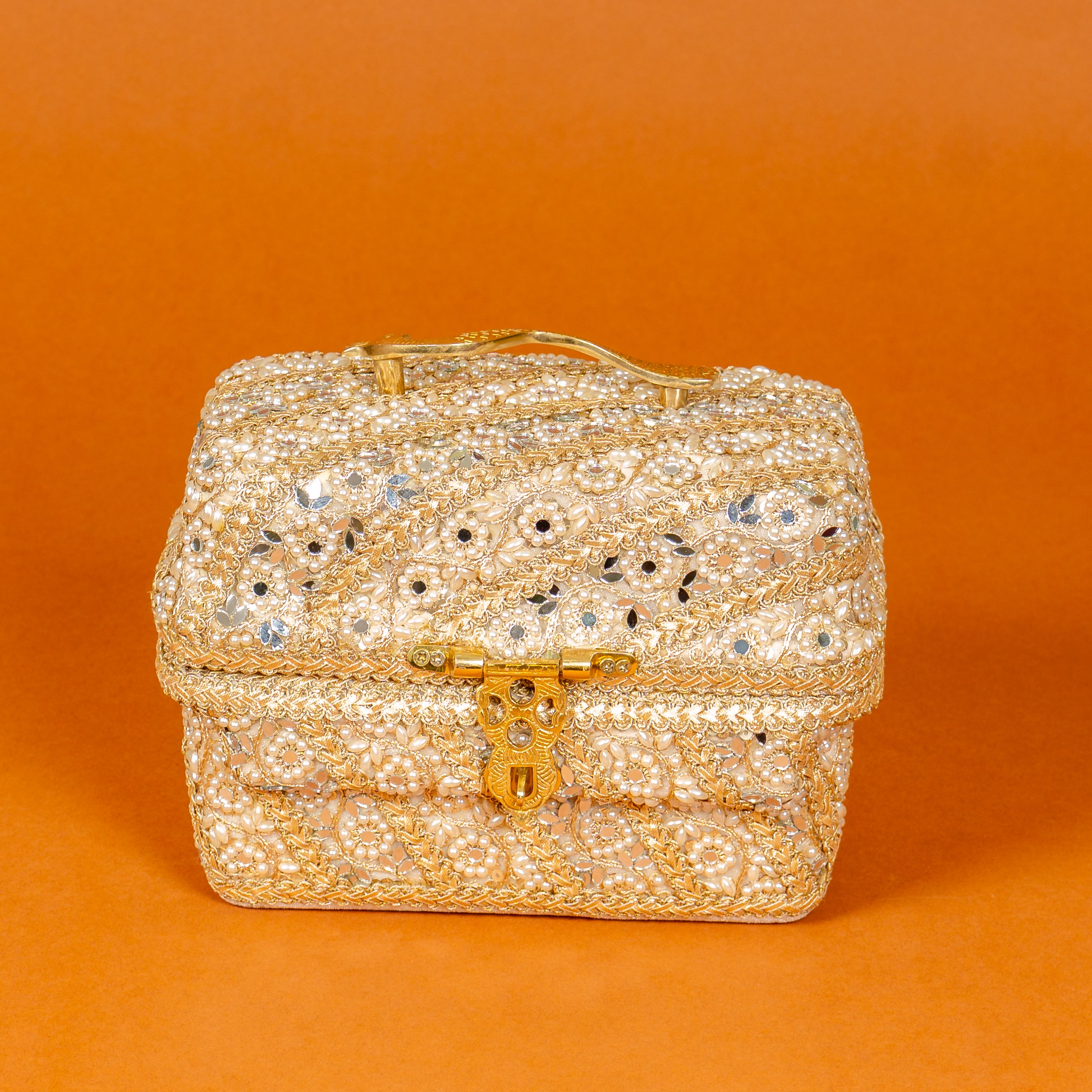 Decorative jewelry box with gold accents and crystals on an orange background