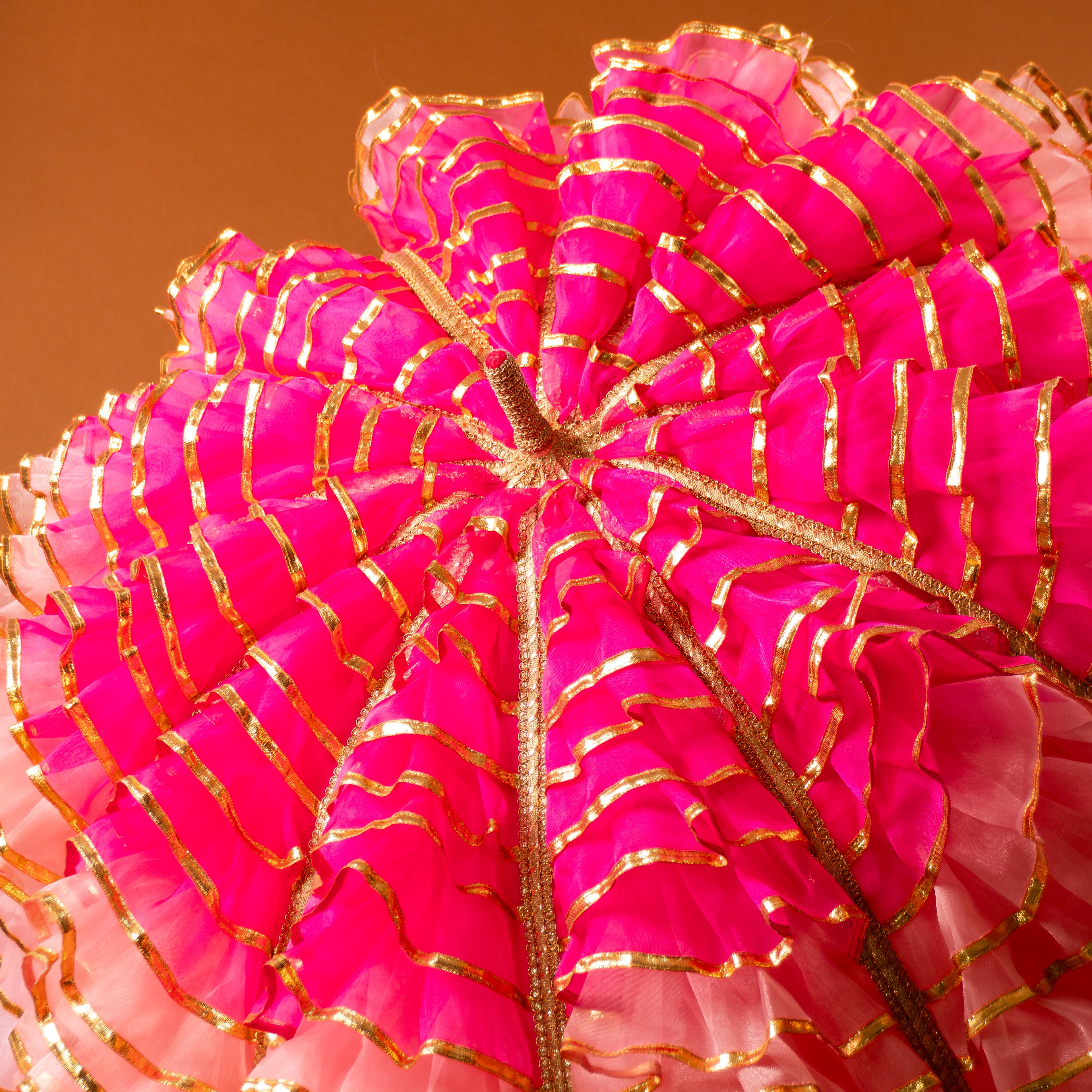 Close-up of a pink decorative umbrella with gold accents on a brown background